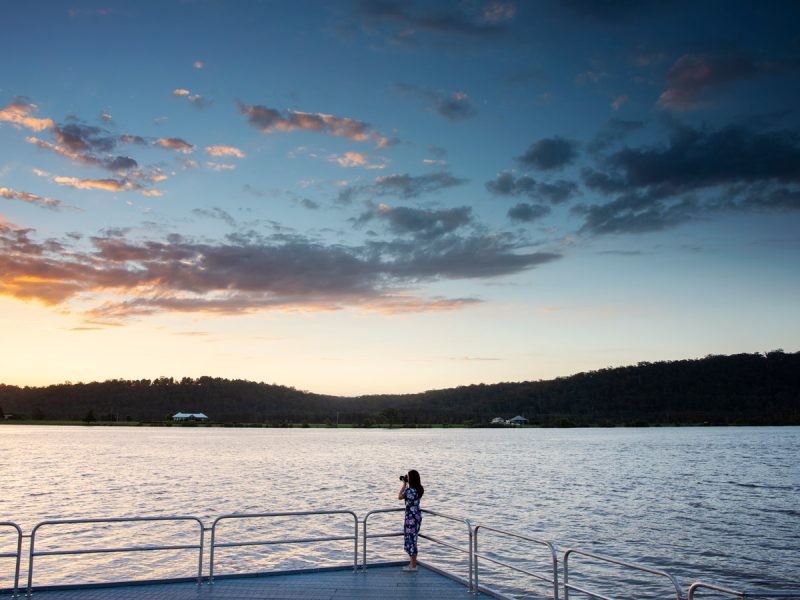 Woman taking photos of the sun setting over the Clarence River, Maclean