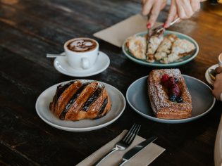 a hand slicing decadent pastries on the table at Wildflour Bakery in Canberra